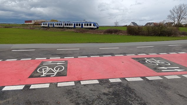 Rote Radwegemarkierung am Bahnübergang West