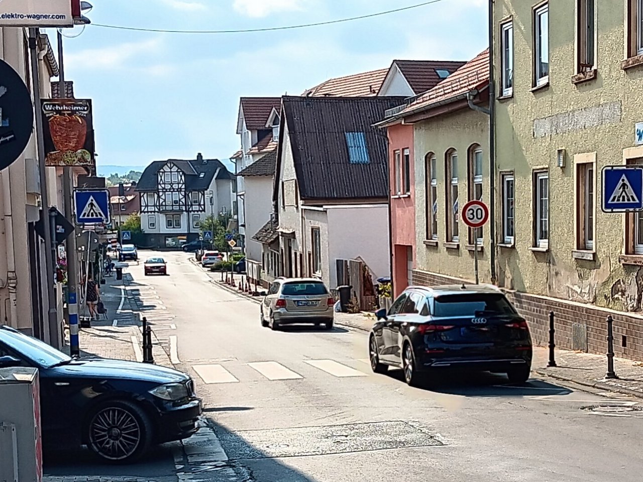 Auf dem Foto sieht man den unteren Teil der Hauptstraße in Wehrheim - gesehen etwa vom Alten Rathaus aus. Auf der linken Seite sind die Parkplätze nicht belegt, auf der rechten Seite finden Bauarbeiten an den Pollern statt. 